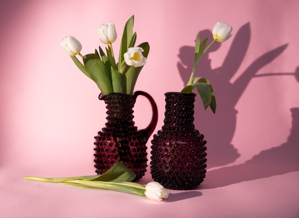 Violet Hobnail Carafe on a pink background with white flowers and shadows