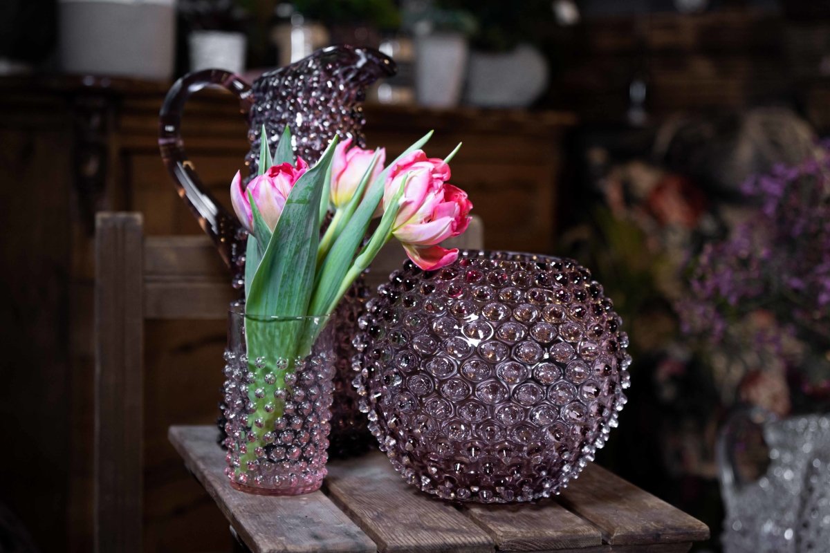Underlay Violet Hobnail Vase on a wooden table surrounded by two objects from the Hobnail collection, against a dark background