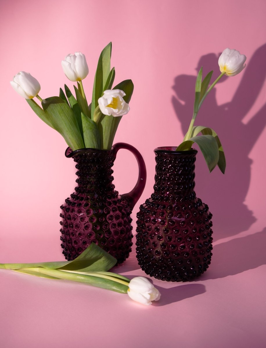 Violet Hobnail Carafe on a pink background with white flowers and shadows