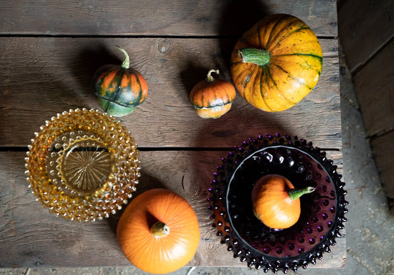 Violet Hobnail Bowl on a wooden table surrounded by pumpkins 