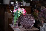 Underlay Violet Hobnail Vase on a wooden table surrounded by two objects from the Hobnail collection, against a dark background 