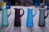 Violet Hobnail Jug Tall on a wooden floor surrounded by the same model in different colors 
