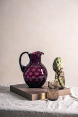 Violet Kugel Jug on a square wooden piece with glasses and artichoke